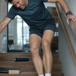 Soulager des courbatures aux cuisses : homme qui ressent la douleur en descendant des escaliers